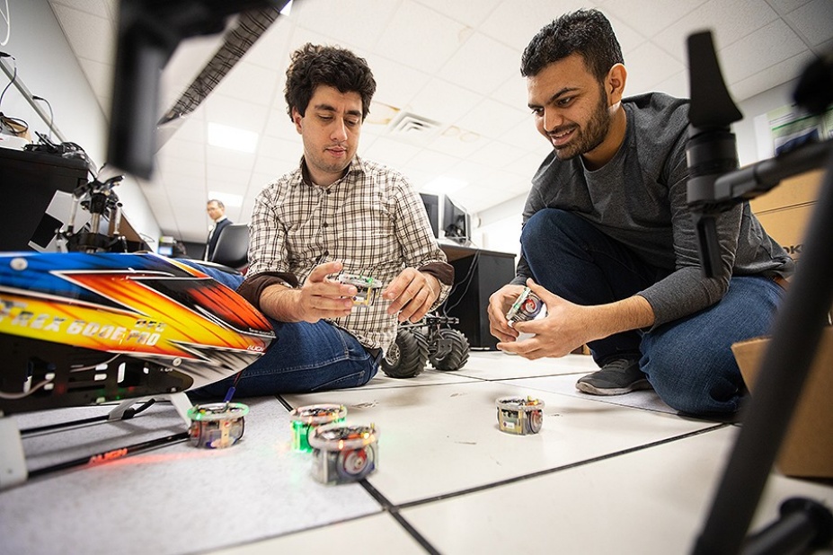 Two UB students work with small drones inside a UB lab.