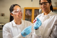 Zoom image: Shermain Aponte (left), a participant in UB&rsquo;s CHEM 360&deg; summer research program, prepares a sample for analysis in a mass spectrometer. With UB chemistry PhD student Grace Guardian (right), Aponte is part of a team that&rsquo;s optimizing analytical methods for detecting per- and polyfluoroalkyl substances (PFAS) in deer tissues. Credit: Douglas Levere / University at Buffalo 