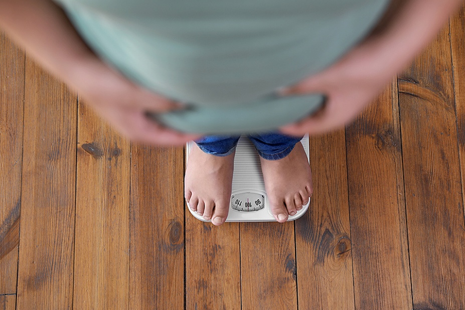 Overweight teen standing on floor scale, viewed from above.