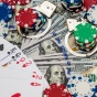 Graphic showing playing cards, poker chips, handcuffs and $100 bills to depict gambling and crime. 