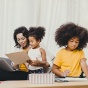 Woman sitting on couch helping two children with school work. 