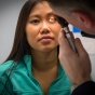 Physician examines patient's eyes with lighted instrument. 