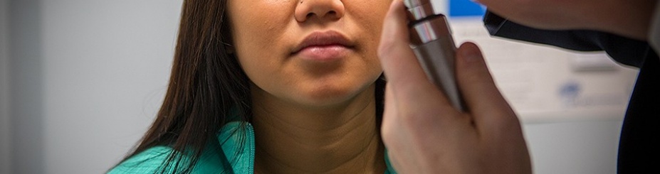 Physician examines patient's eyes with lighted instrument. 