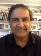 Portrait of Surajit Sen, with bookshelves behind him. 