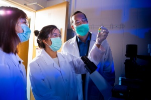 Zoom image: Wei-Chiao Huang (center), director of vaccine development for University at Buffalo spinoff POP Biotechnologies, holds a vial containing ingredients of a COVID-19 vaccine under development. To her left and right, respectively, are POP Biotechnologies team members Xuedan He and Jonathan Lovell. Credit: Douglas Levere / University at Buffalo 