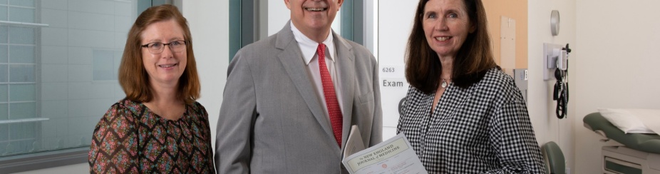 Steve Lipshultz, (center) chair of the Department of Pediatrics, with Lucy Mastrandrea, (left) and Kara Kelly, (right) who is holding a copy of the journal. All three are standing in a hallway. 