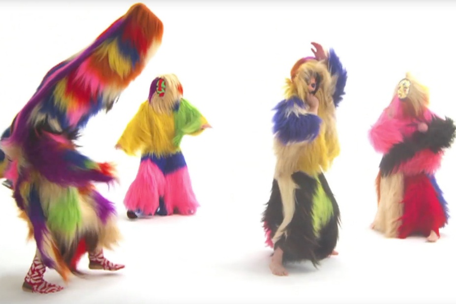 Video still from "Nick Cave's Soundsuits" featuring dancers in colorful, shaggy full-body costumes. 
